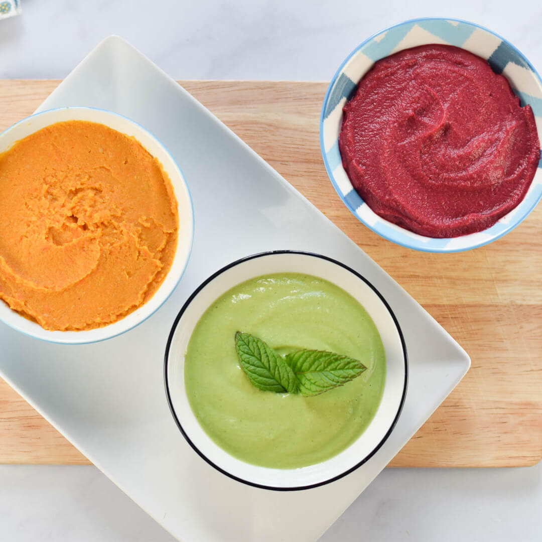 Bowl of Pea & Mint Dip next to a bowl of orange dip and a bowl of red dip