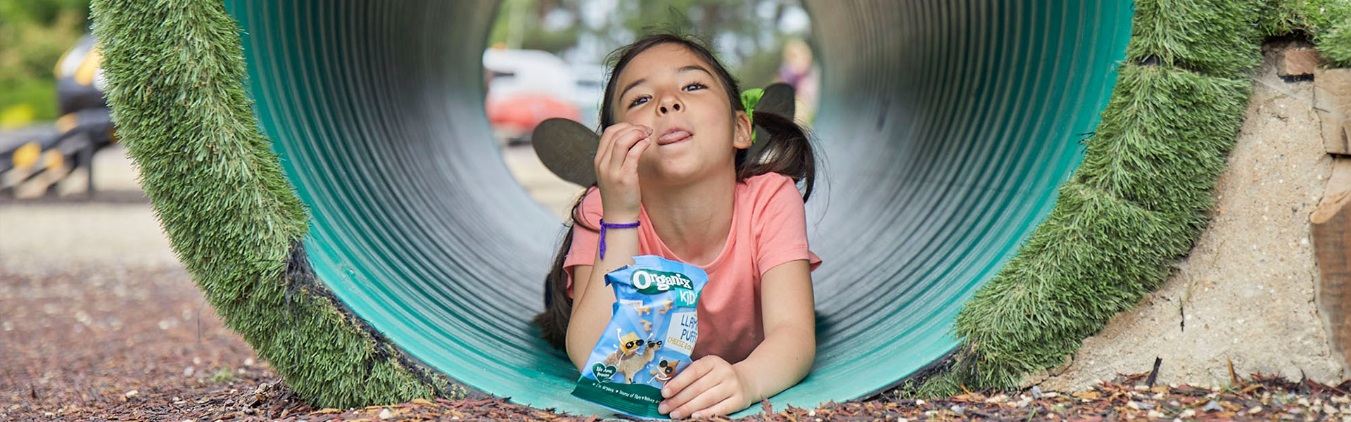 Girl eating Puffs in a play-tunnel
