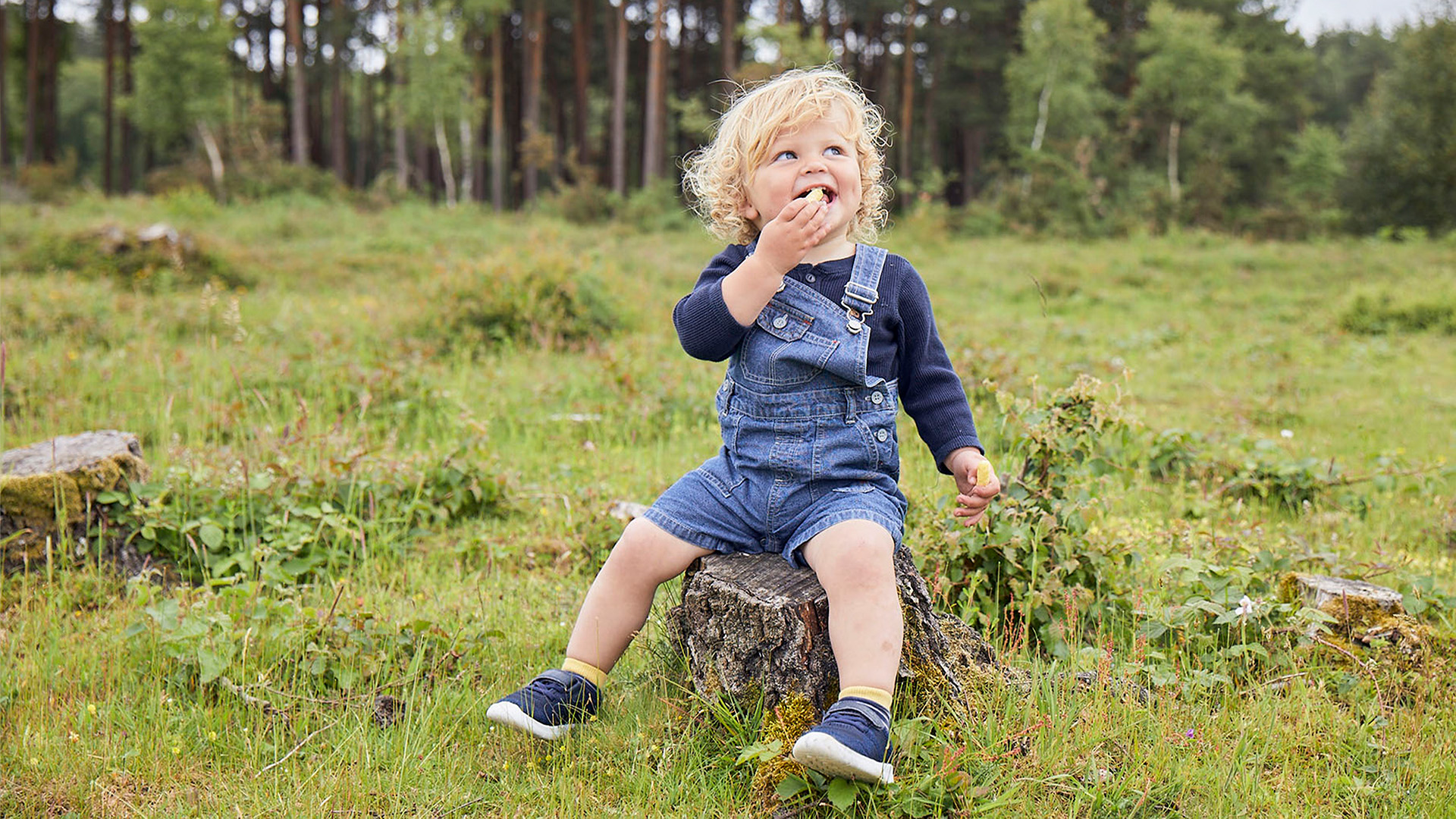 Boy toddler eating Organix snack in the woods