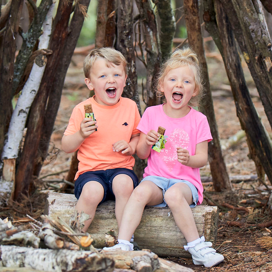 Two children sat outdoors eating Organix snacks