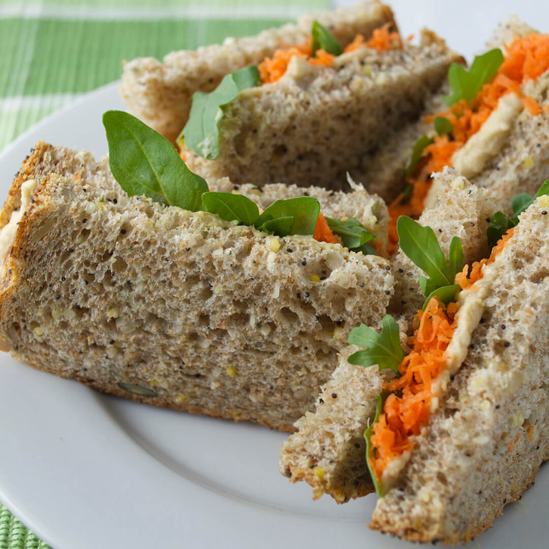 A plate of grated carrot and hummus sandwiches