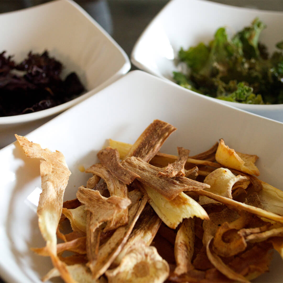 Vegetable crisps: a bowl of parsnip crisps next to bowls of red and green kale crisps