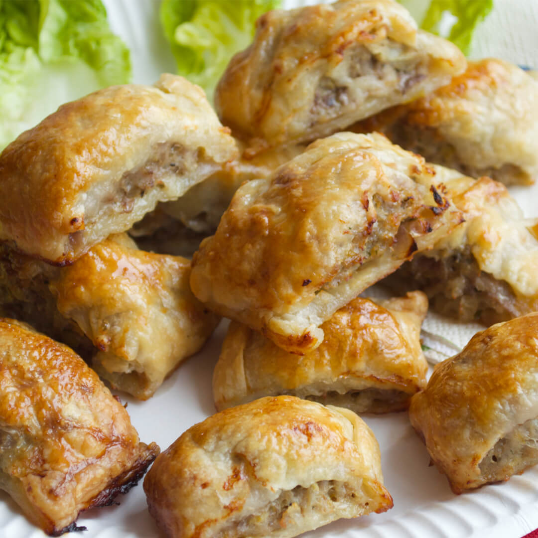 A plate of mini sausage rolls with some lettuce leaves