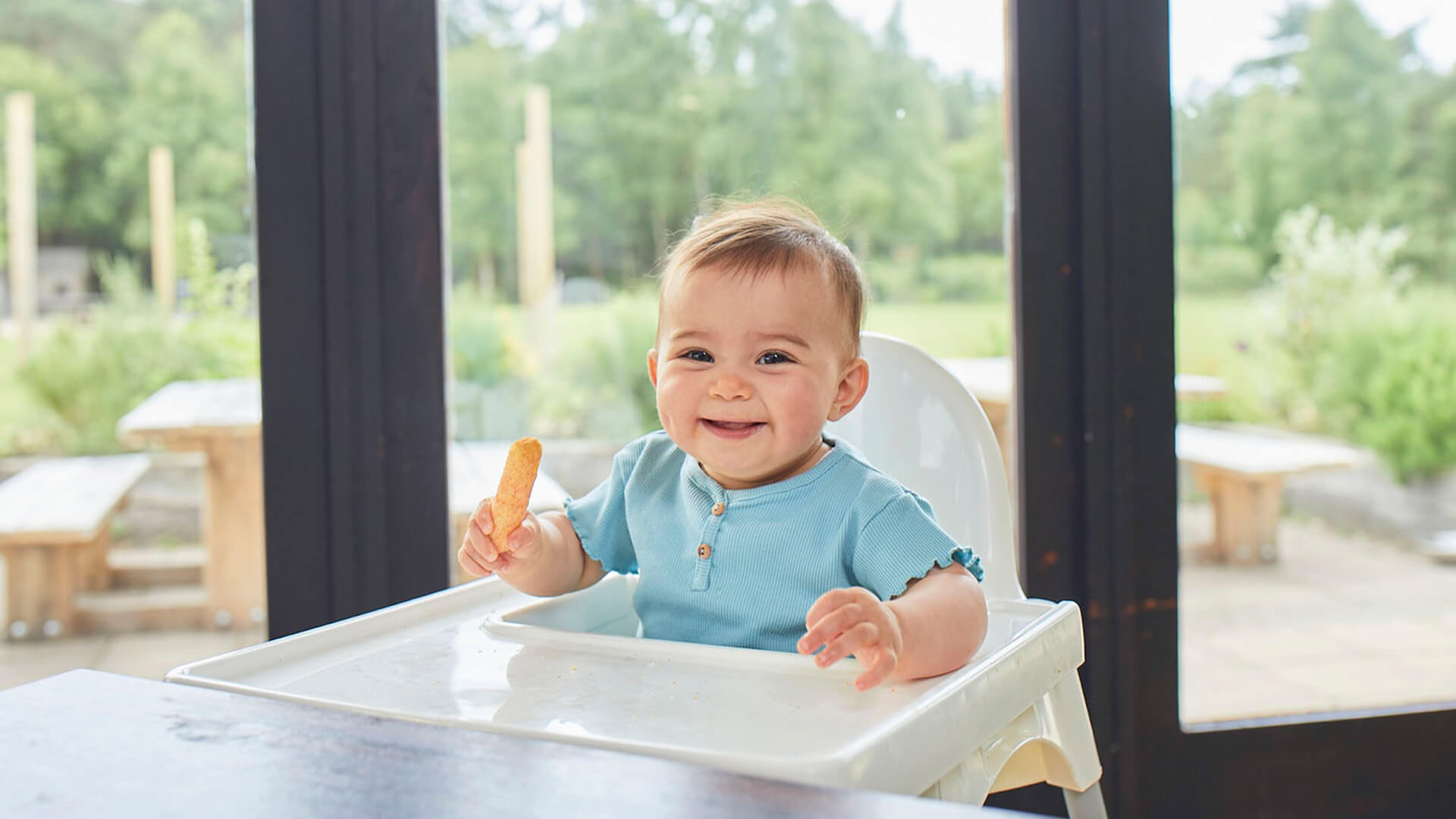 A baby sitting on a high chair and eating