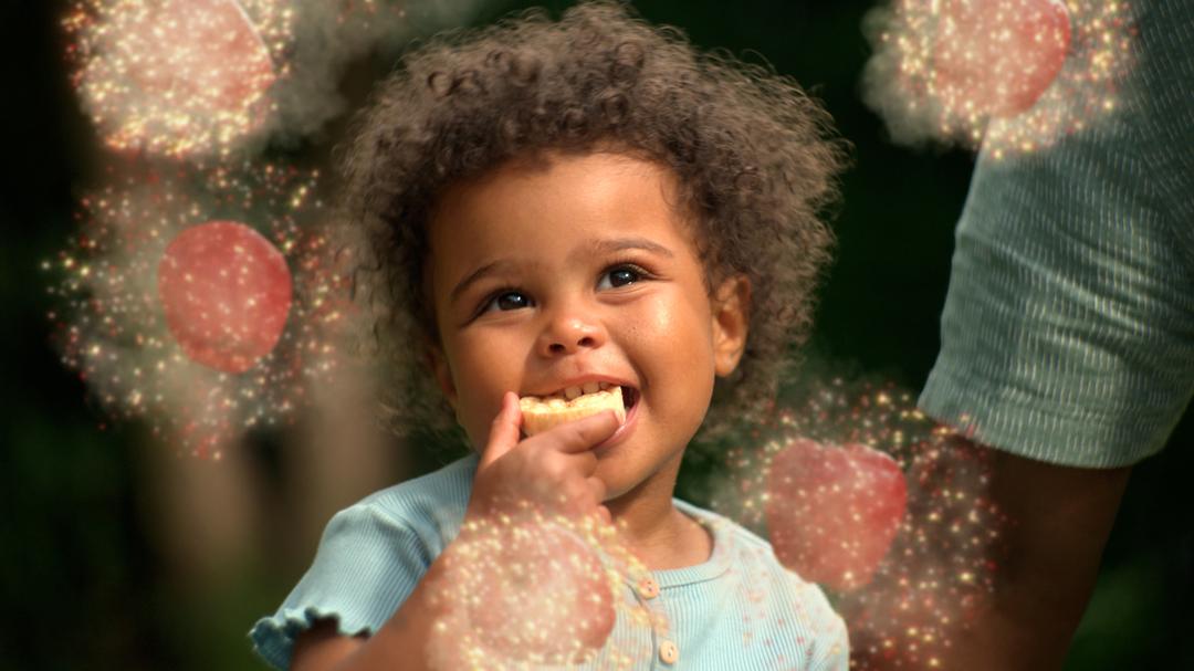 Baby eating an Organix Rice Cake Cloud and with a rainbow of sparks around their head