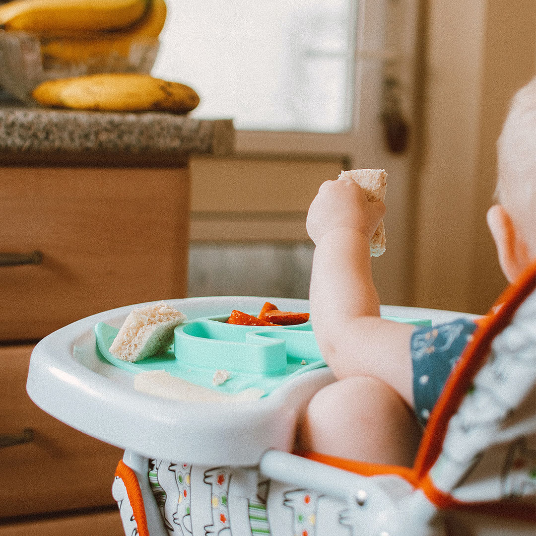 A baby sitting on a high chair and eating