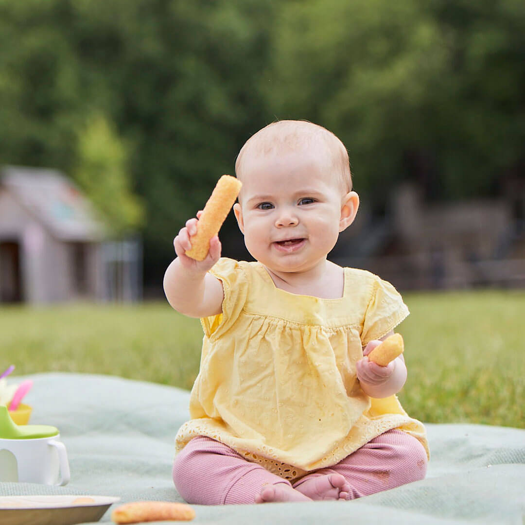 A smiling baby holding some food