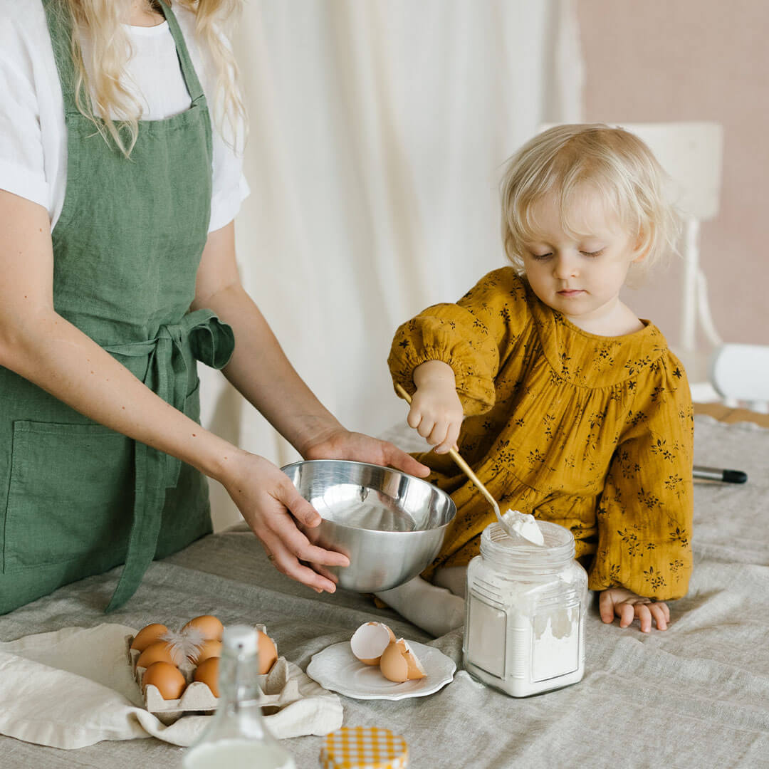 A toddler and an adult baking together