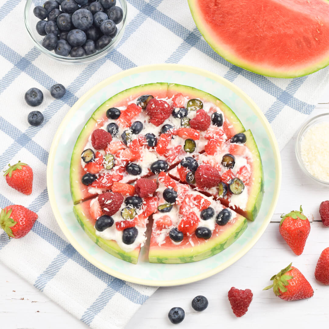 Watermelon pizza topped with yoghurt, blueberries, raspberries, strawberries and desiccated coconut 