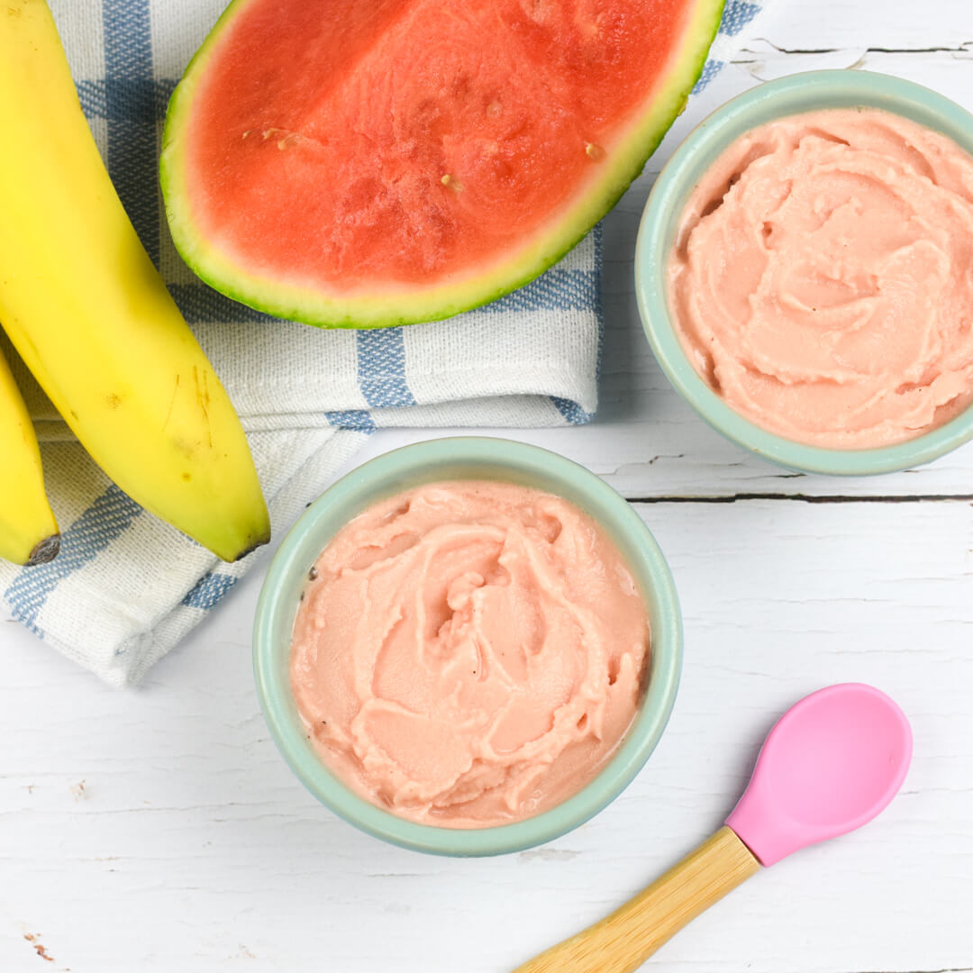 A small bowl of watermelon nice cream next to a sliced watermelon and some bananas