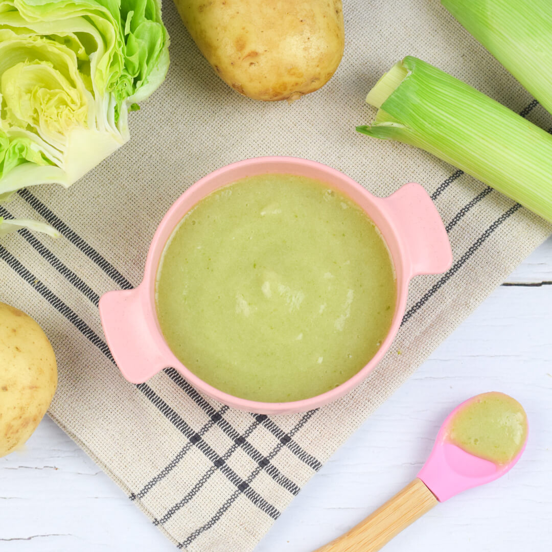 A bowl of Lettuce, Leek and Potato Puree next to a halved lettuce, some potatoes and leeks