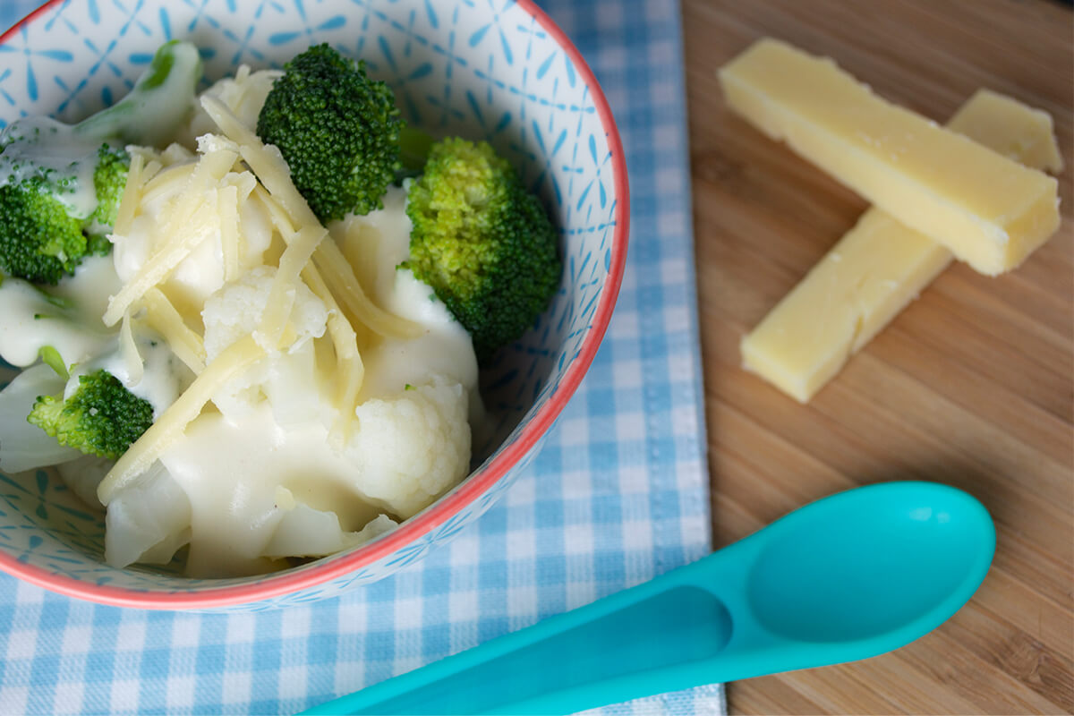 Baby Cauliflower & Broccoli Cheese in a bowl next to some cheese sticks