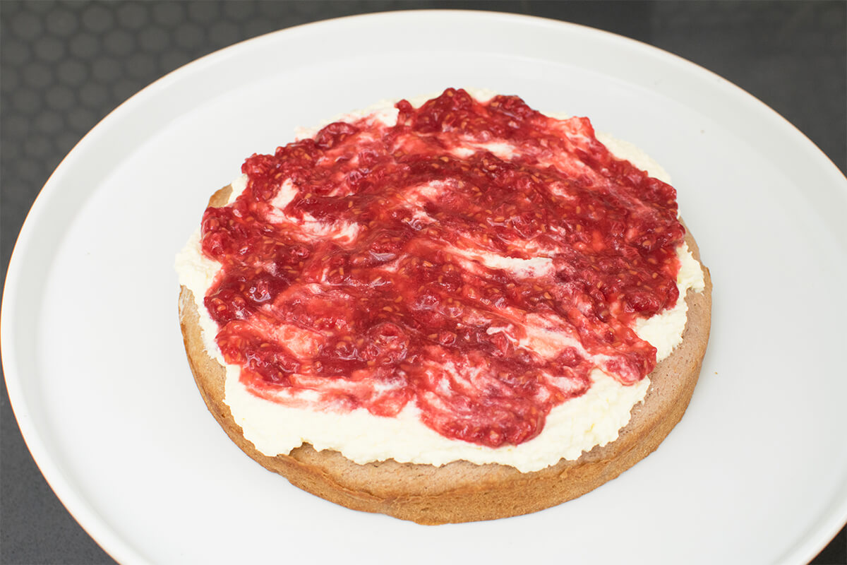 Half a cake topped with cream as raspberry mixture