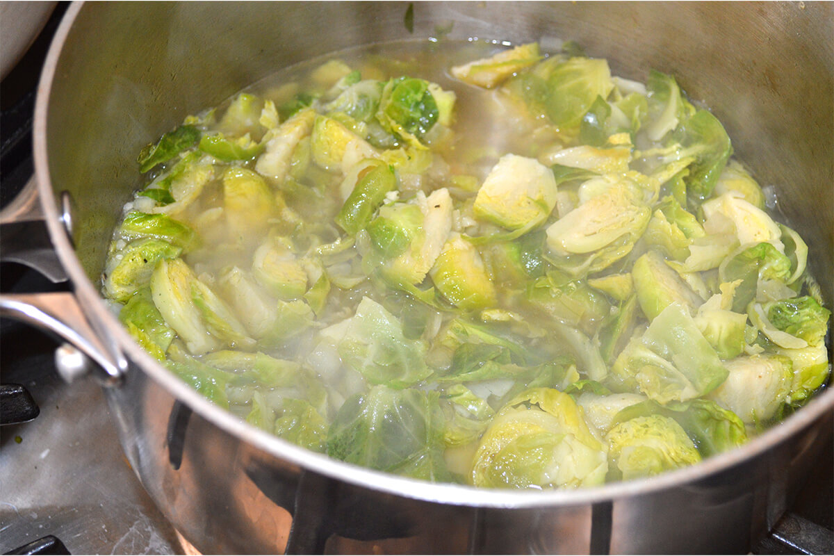 A saucepan of Brussels sprouts, garlic and stock