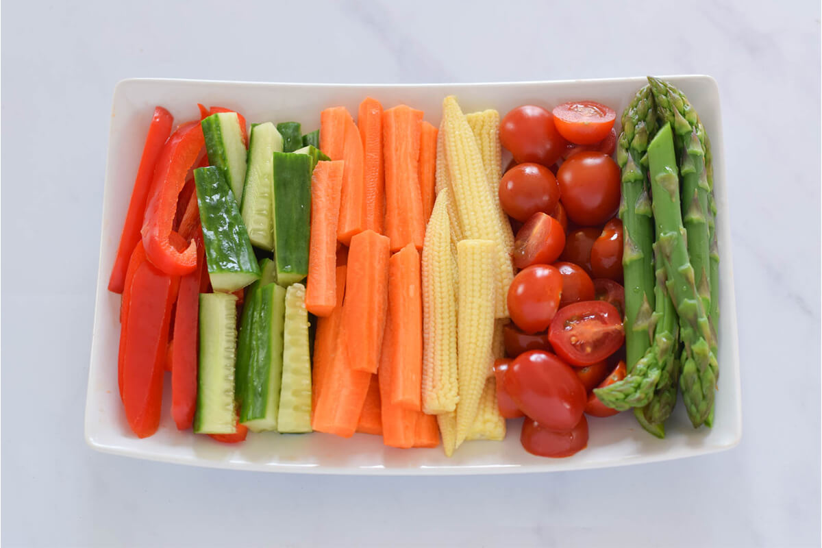 Veggie Crudités platter with red pepper, cucumber, carrot, baby corn, cherry tomatoes and asparagus tips
