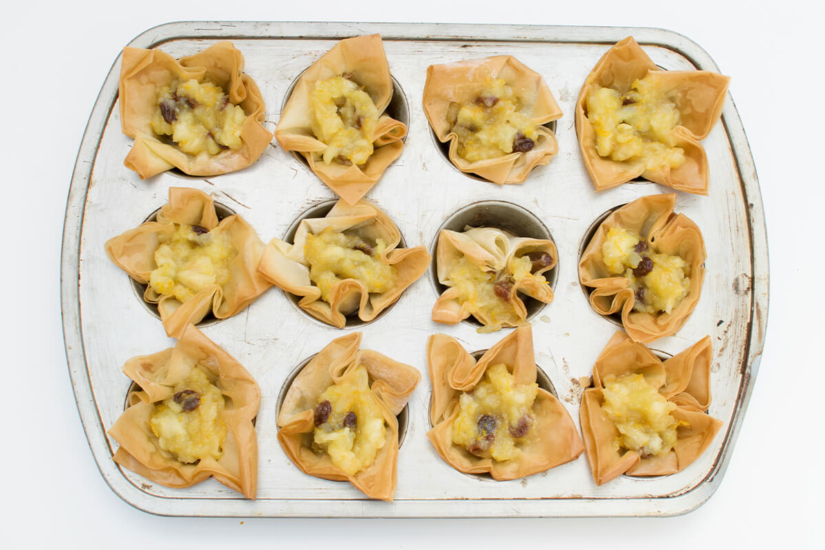 A cake tin with baked filo pastry filled with apple mixture