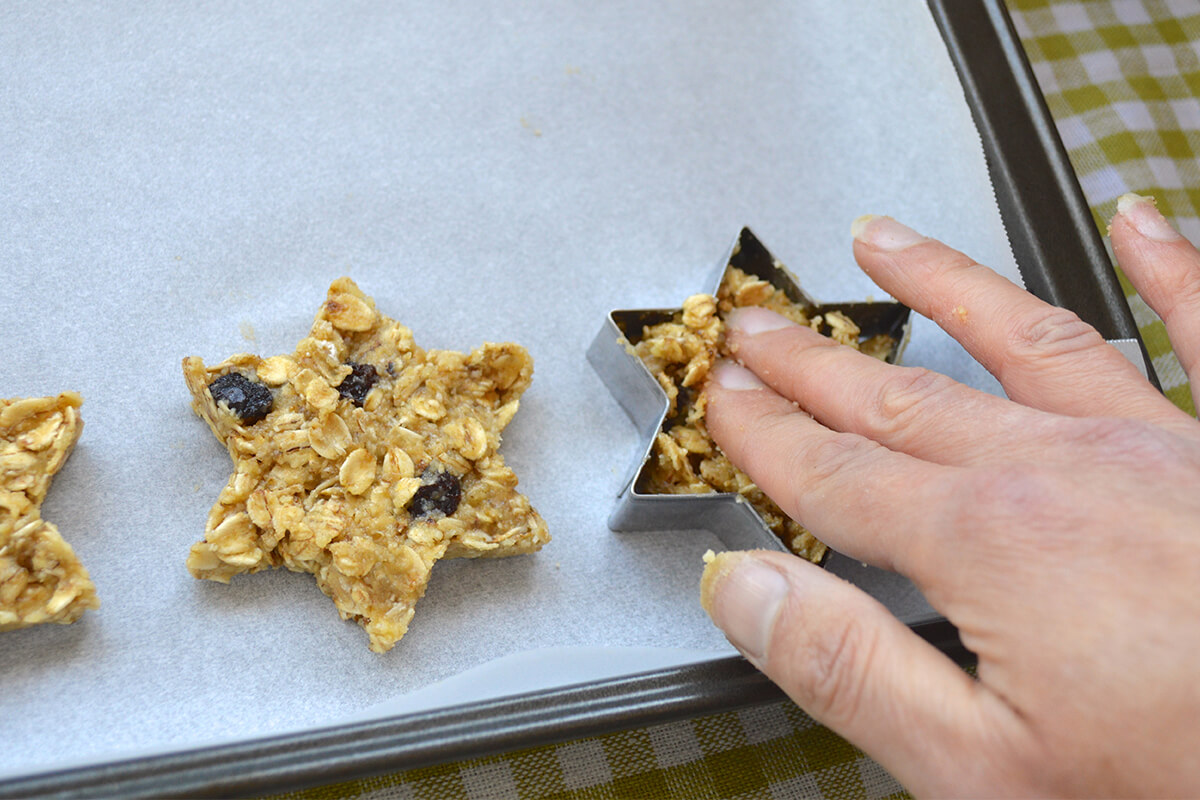 Star shaped biscuit mix being placed on a lined baking tray