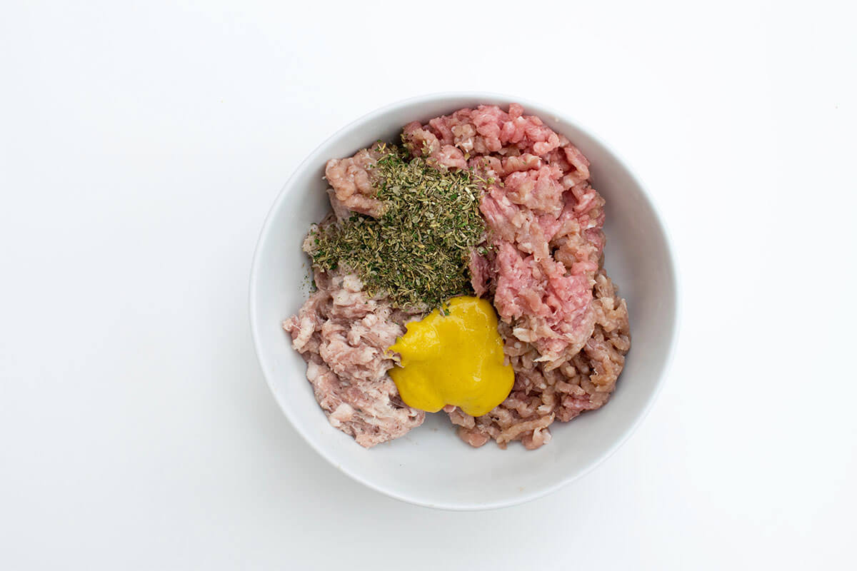 A bowl of sausage and turkey mince mixed with mustard, mixed herbs and nutmeg