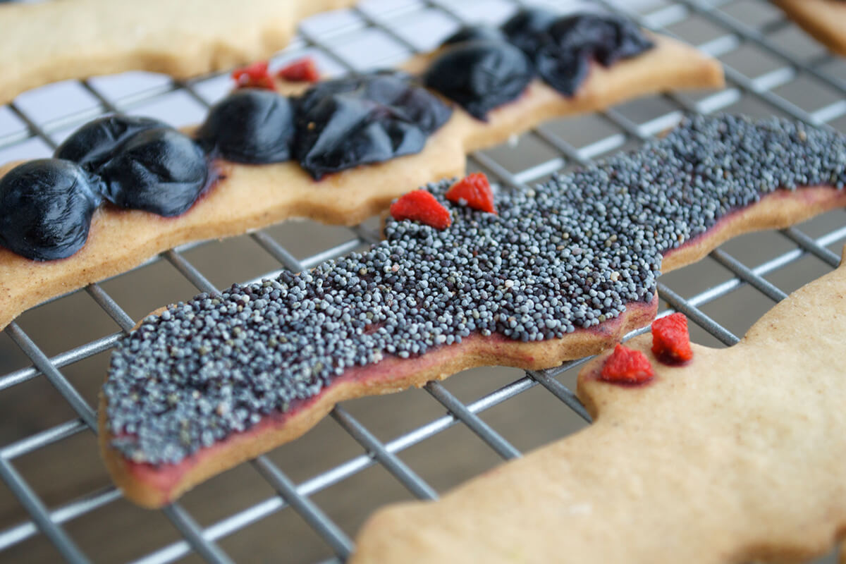 Bat shaped biscuits on a cooling rack, decorated with dried berries and seeds