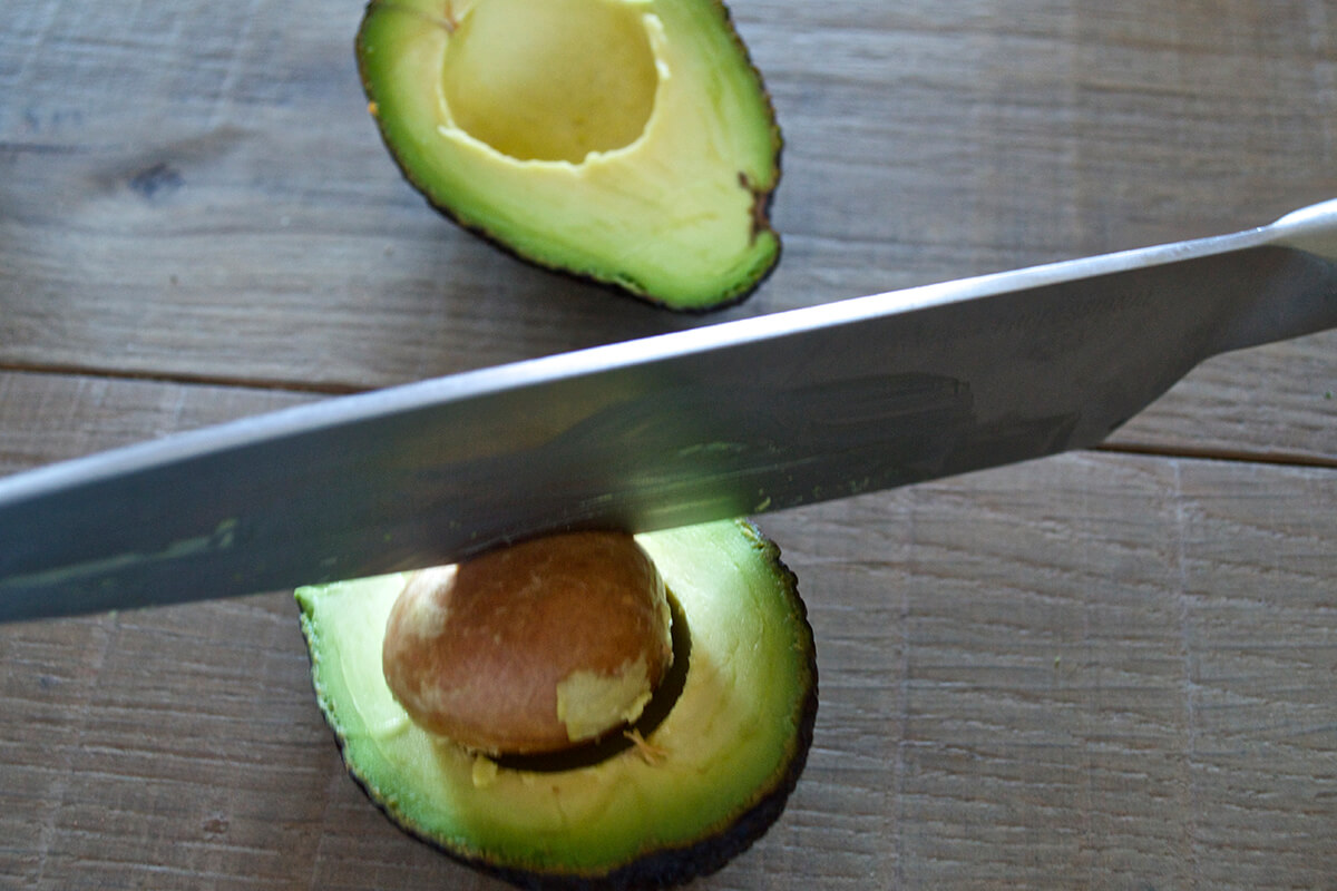 A halved avocado with the stone being removed