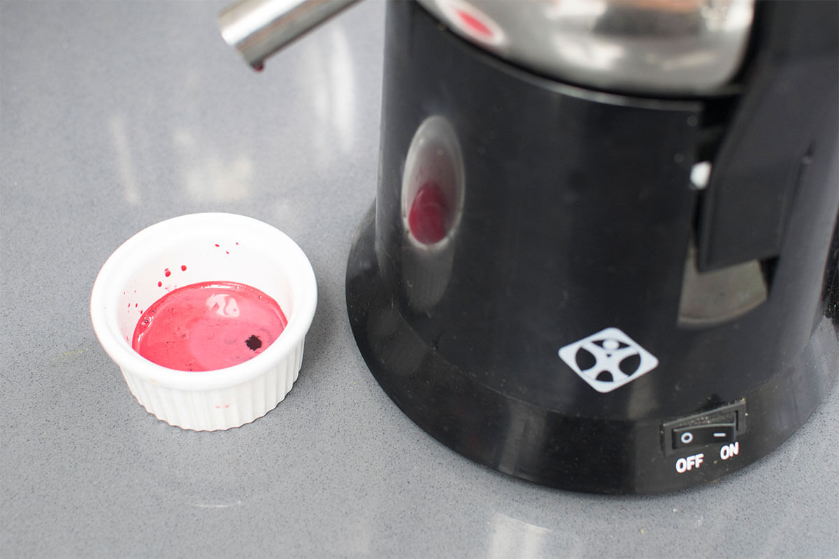 A juicer with some red vegetable juice being made