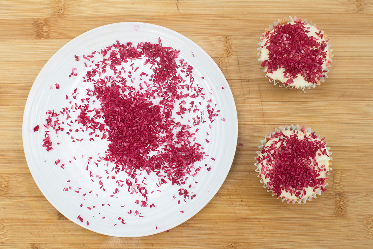 2 cupcakes decorated with red coloured desiccated coconut