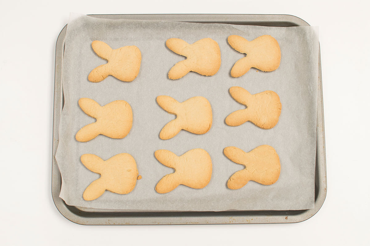 A lined baking tray with 9 bunny shaped biscuits on it