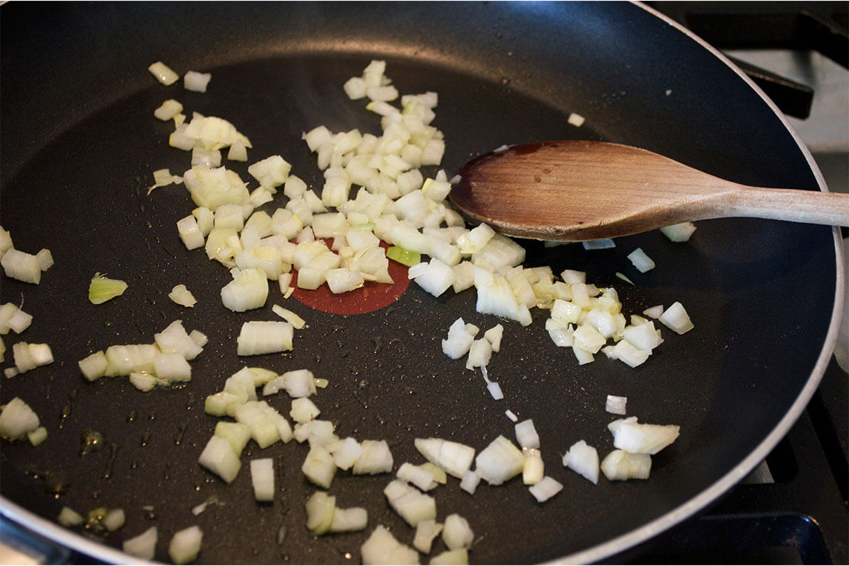 A frying pan with chopped onion being fried