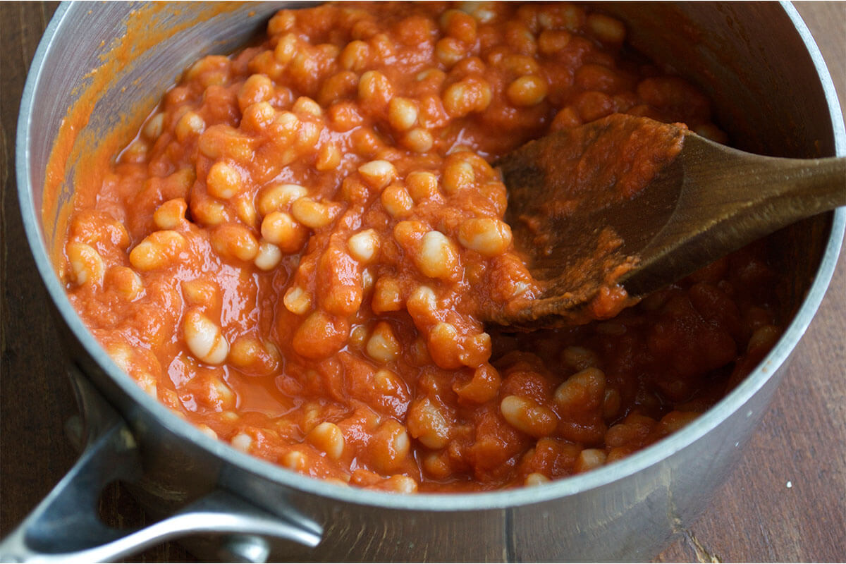A saucepan with blended tomato-based baked bean sauce and beans
