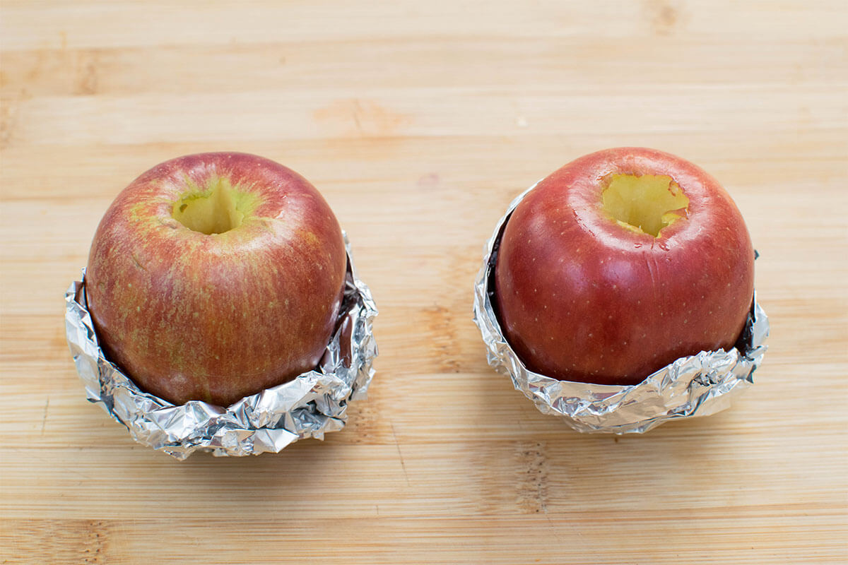 2 cored apples with foil wrapped around the bottom half of them
