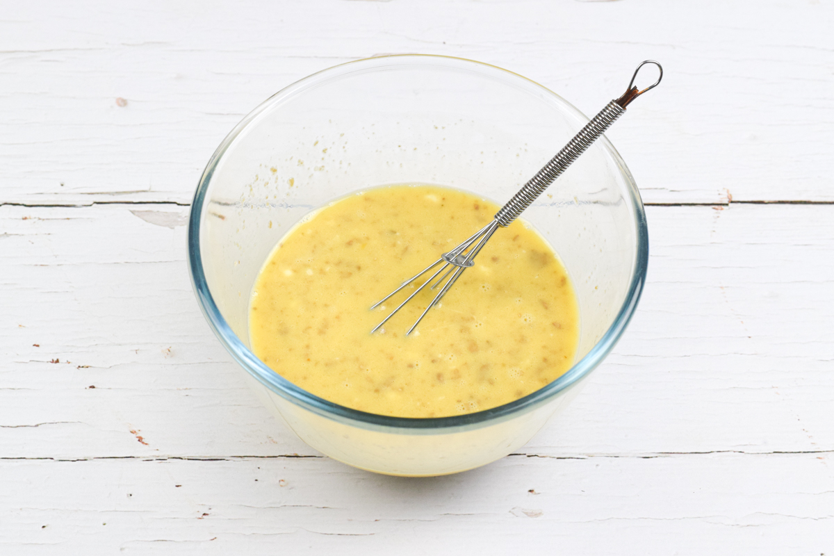 A glass bowl with eggs, milk, mushroom and mozzarella being whisked