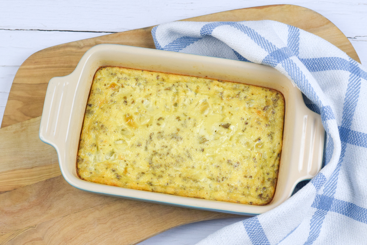 A casserole dish with cooked mushroom omelette on a wooden chopping board