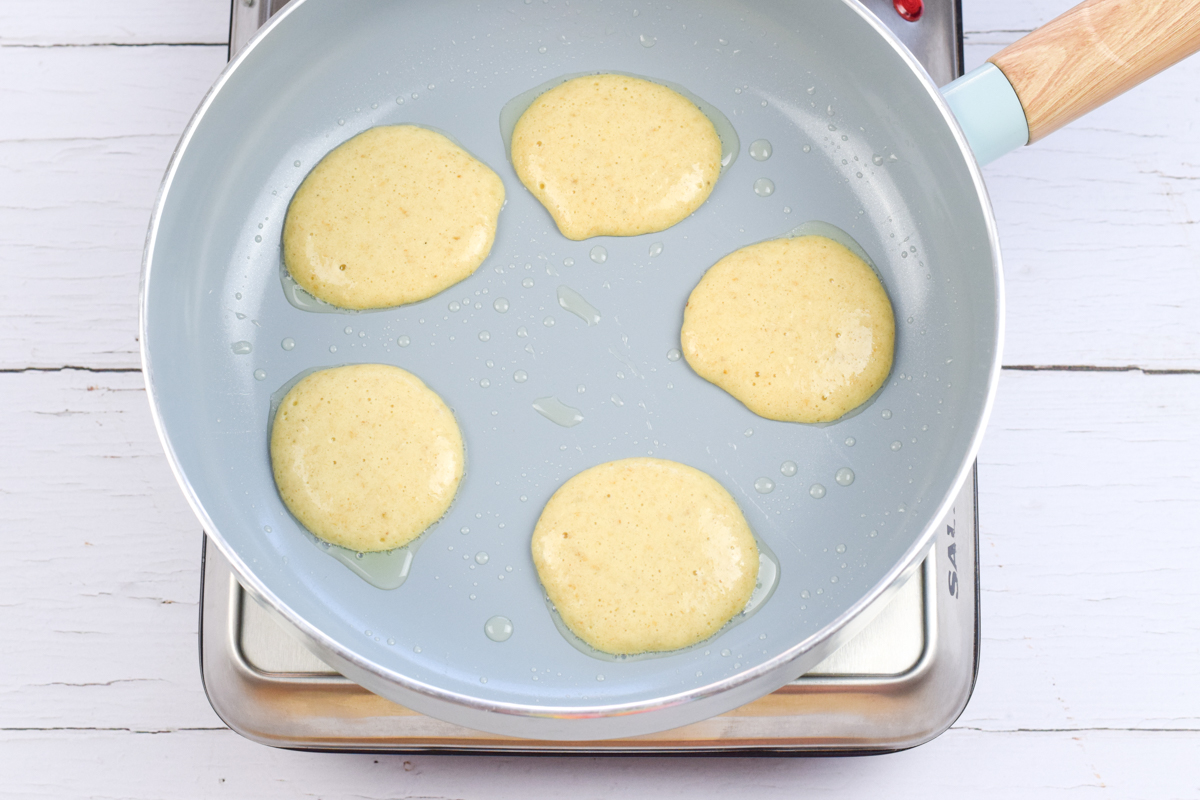 A frying pan with mini pancakes being fried