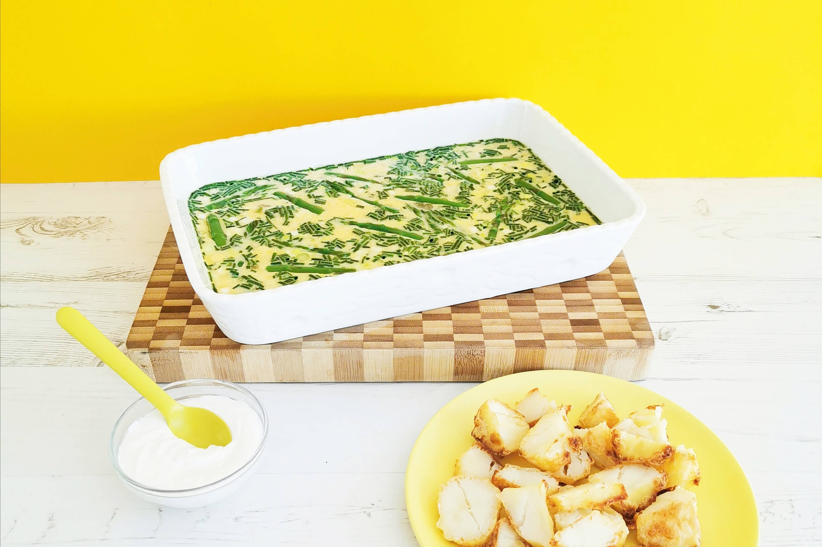 Asparagus & Goats Cheese Frittata in a casserole dish next to a bowl of potatoes