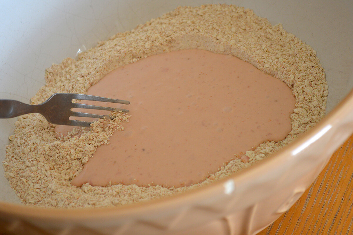 Strawberry muffin batter in a mixing bowl being mixed with a fork