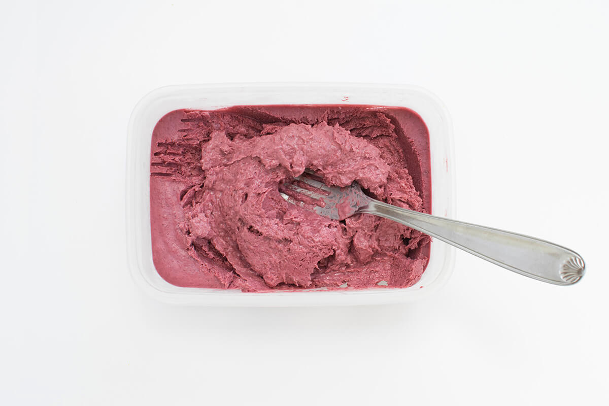 Frozen blackberry and banana ice cream mix in a tub
