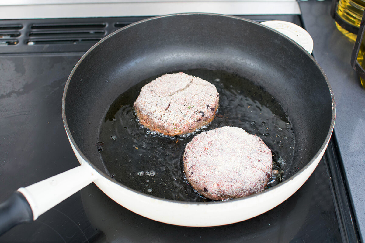 Beetroot burgers being fried in frying pan