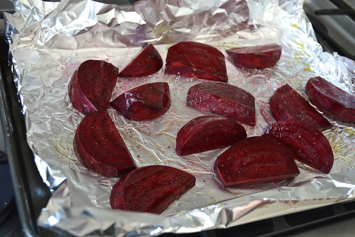 Sliced beetroot on foil on an oven tray