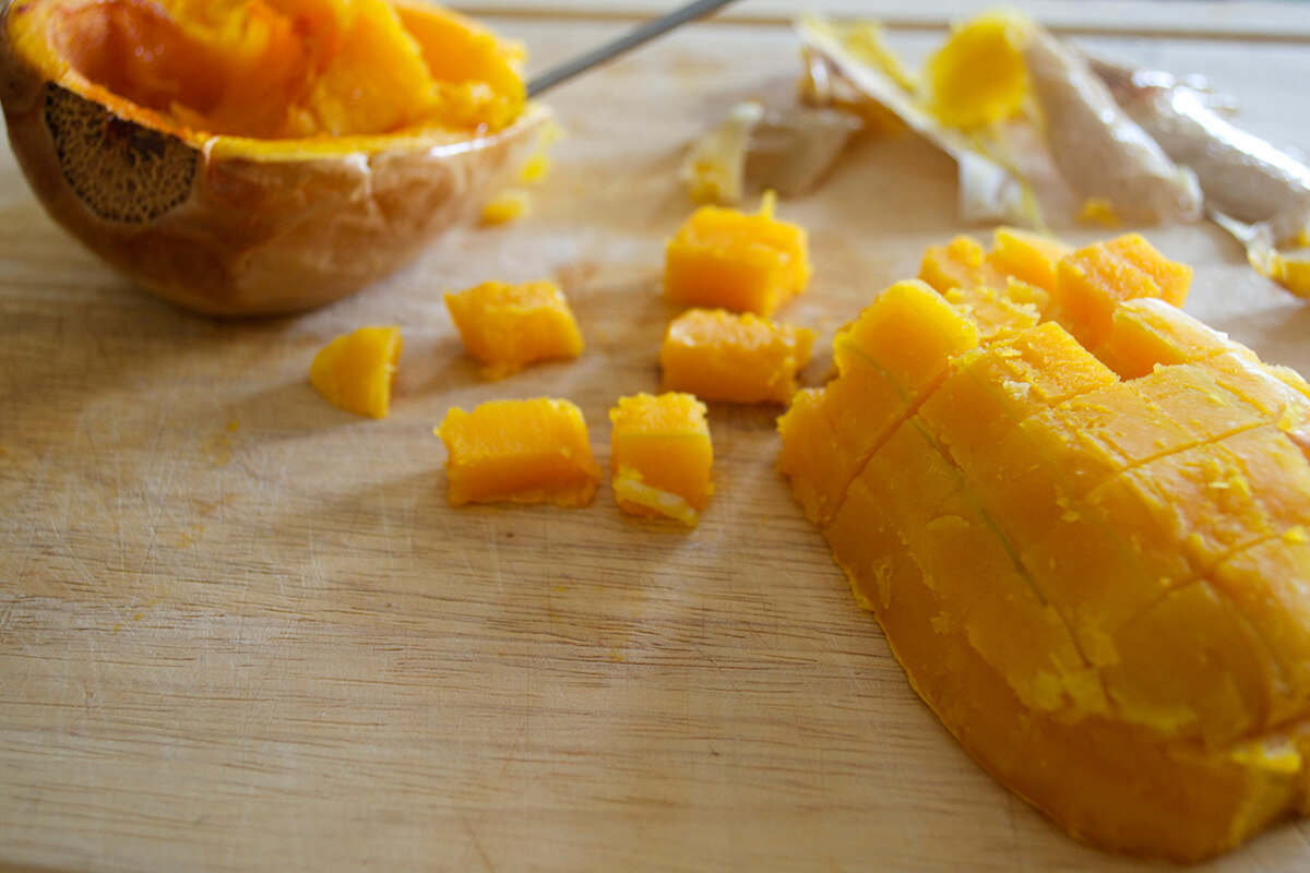 Cooked butternut squash on a chopping board and partially diced 