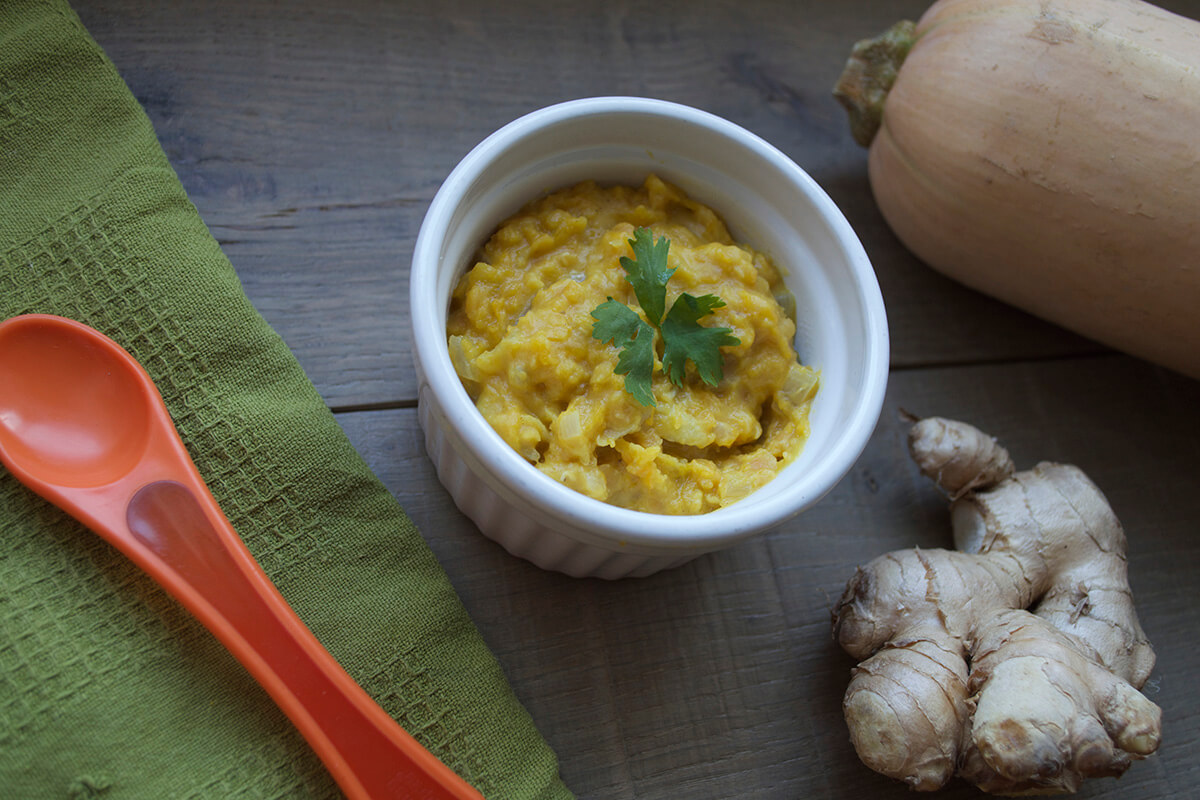 A bowl of butternut squash and ginger puree next to a whole butternut squash and ginger root