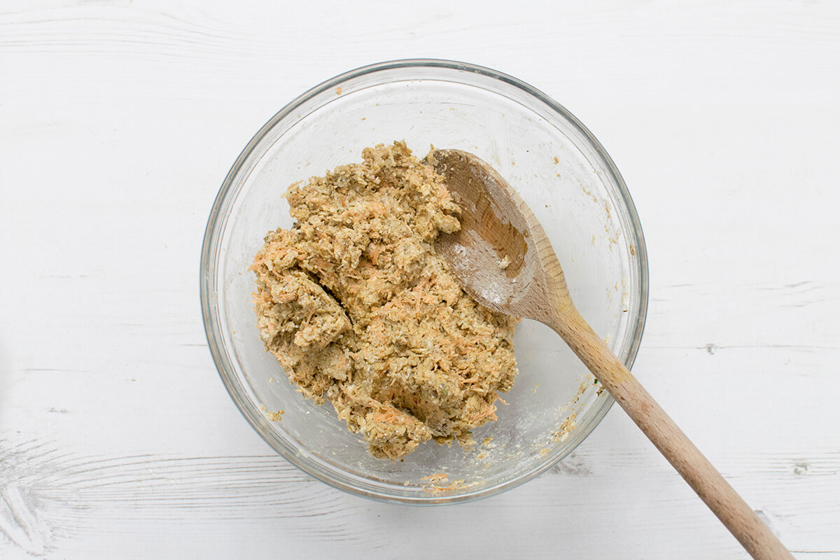 A bowl of oats and spices with oat flour, grated carrot and cheese and beaten egg
