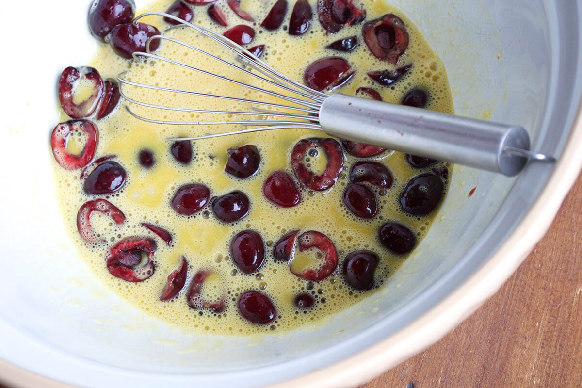 A bowl of eggs being whisked with chopped cherries
