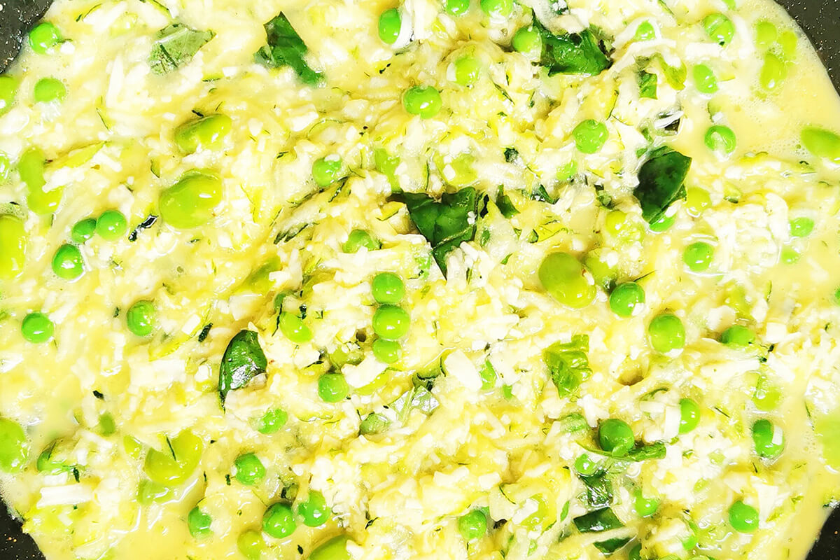A frying pan of Courgette, Pea & Bean Frittata mix being fried