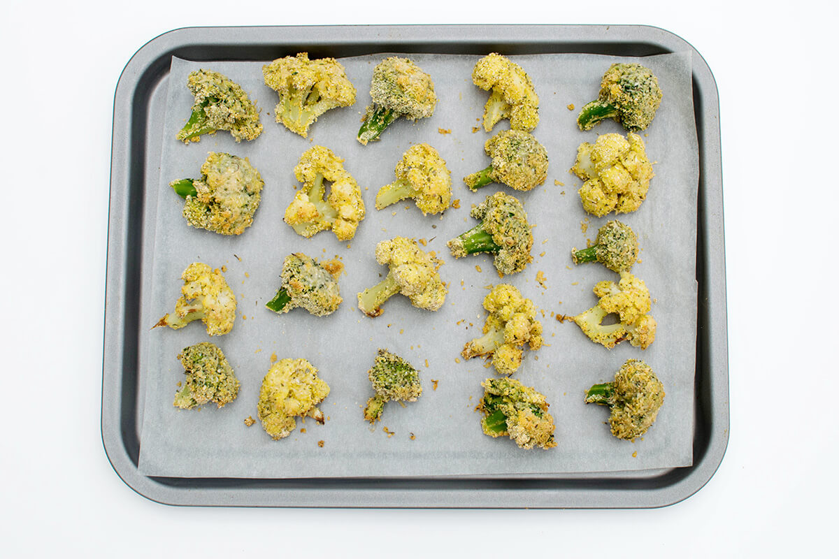 An oven tray of cooked, coated cauliflower and broccoli florets