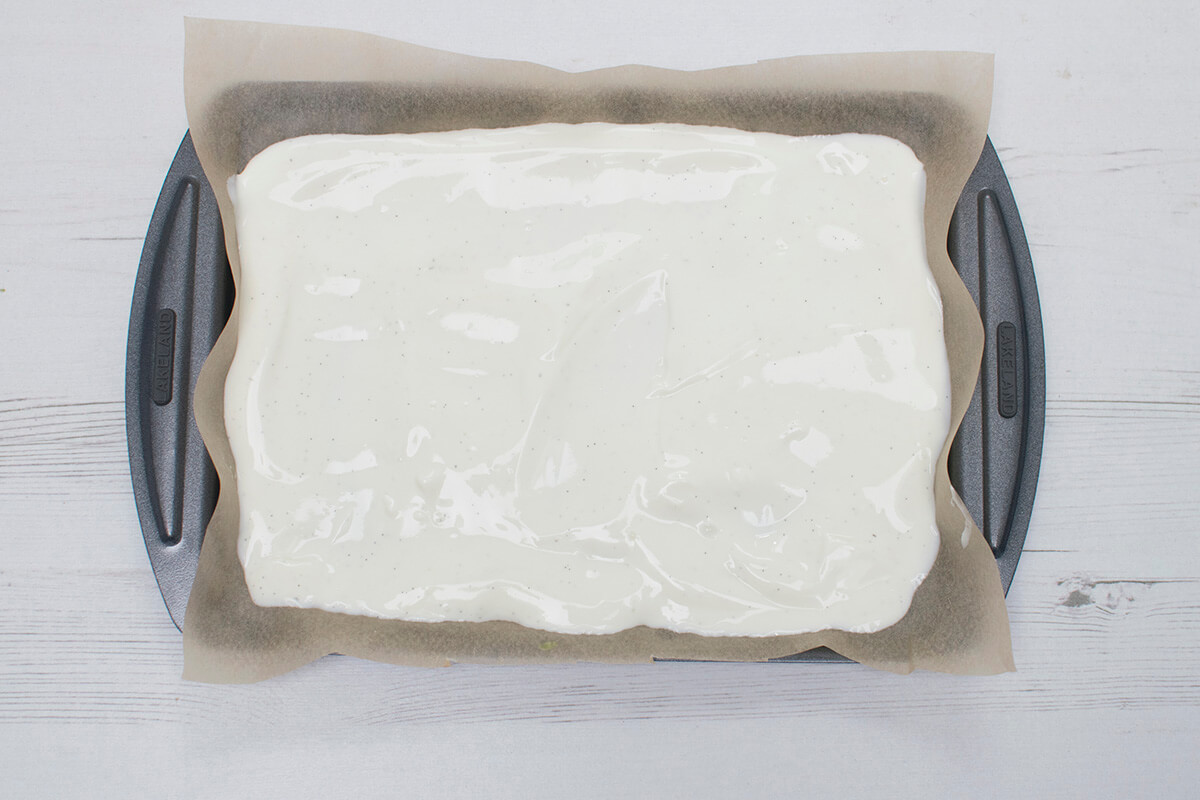 A lined baking tray filled with yoghurt-vanilla mixture