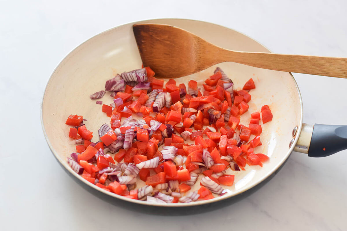A saucepan with chopped red onion and red pepper
