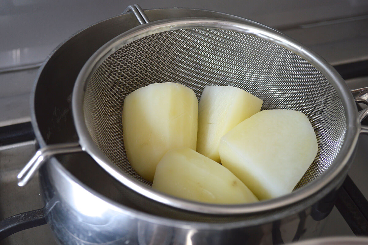 Potatoes being steam dried over a saucepan