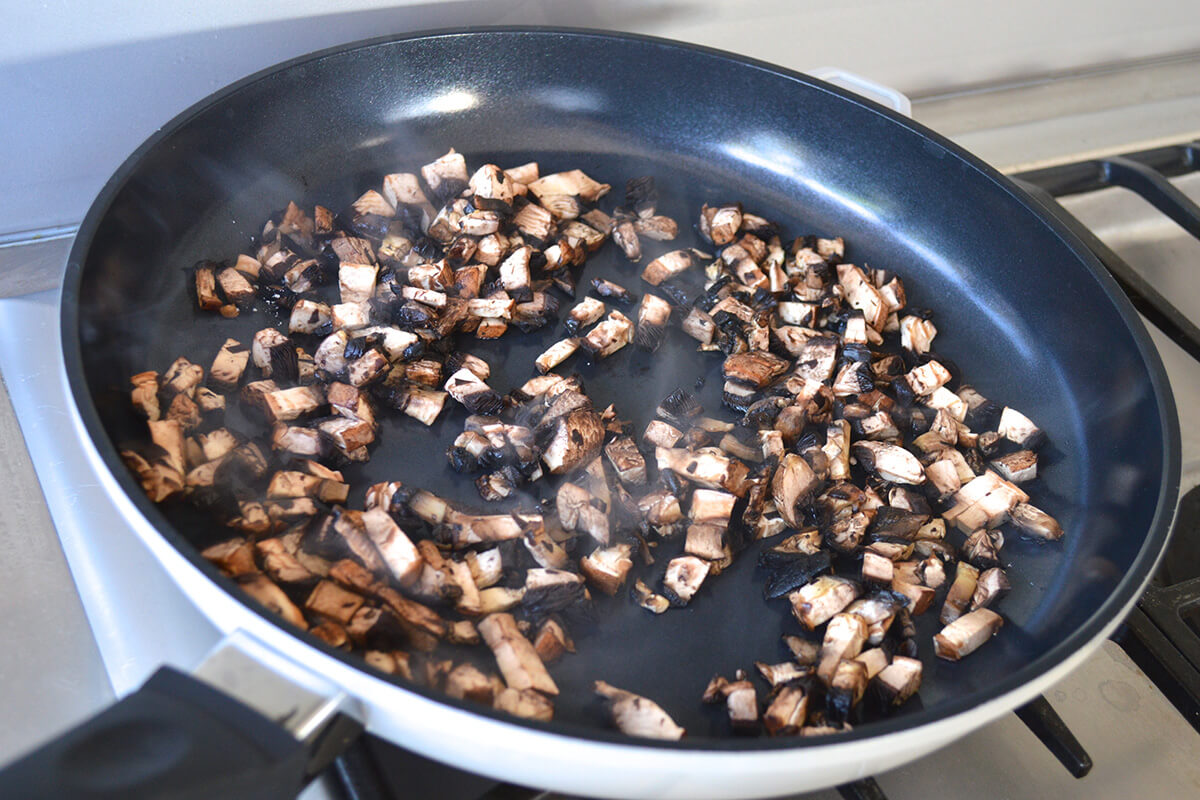 Chopped mushroom being sauteed in frying pan