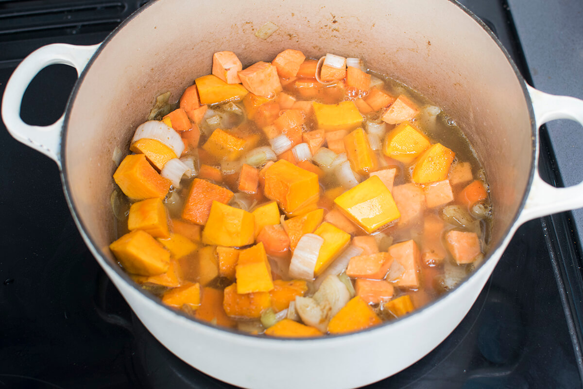 A saucepan with diced leeks, onion, carrots, sweet potato, pumpkin and water