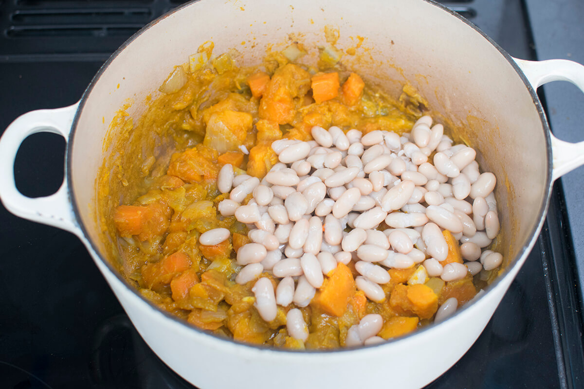 A saucepan with diced leeks, onion, carrots, sweet potato, pumpkin and cannellini beans